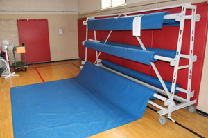 lot 21 image: Gym floor covering - 6 rolled floor mats and rolling cart LOT